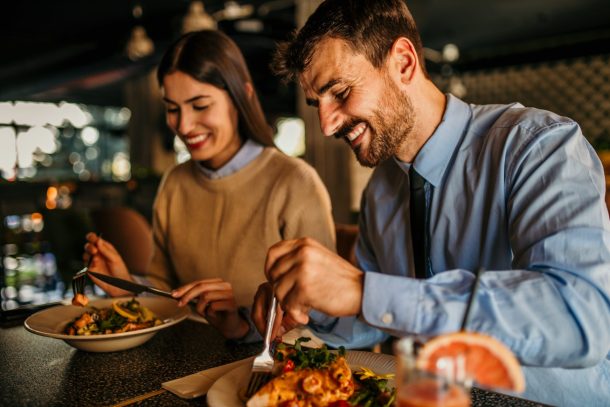 uomo e donna sorridenti mangiano carne