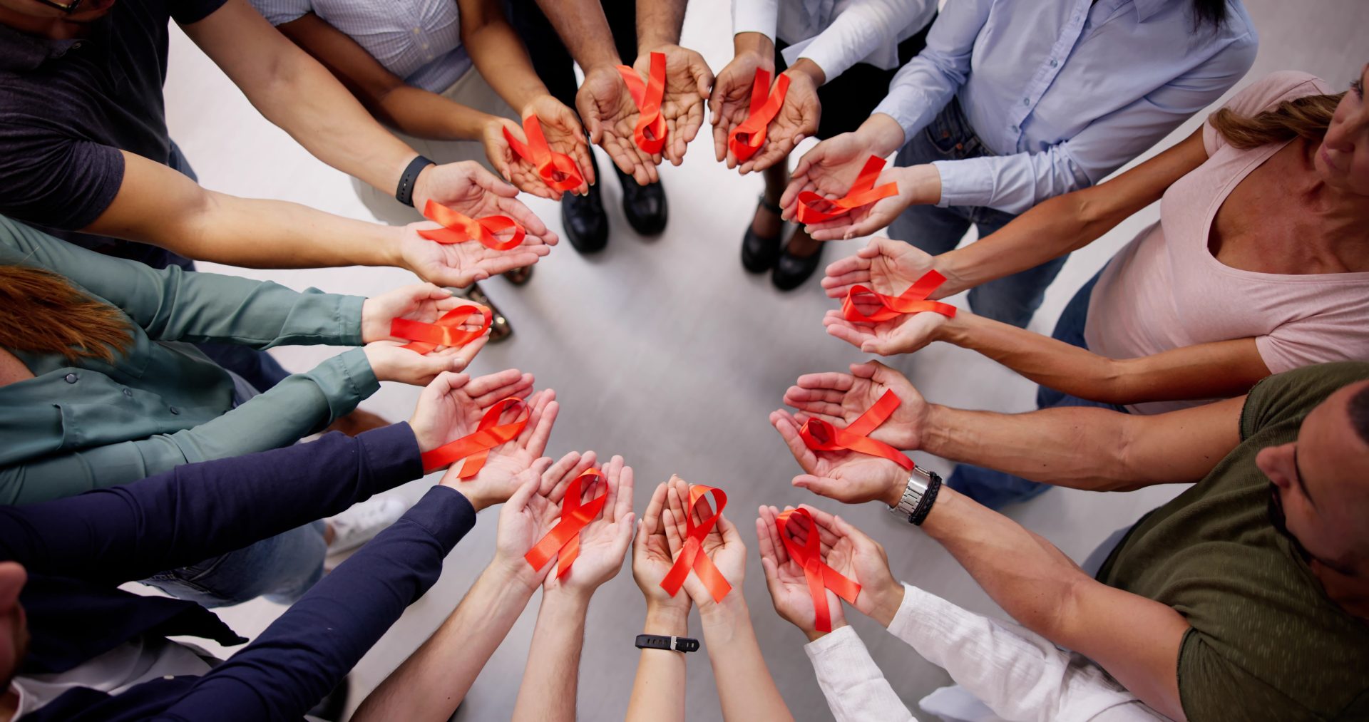 persone in cerchio con in mano fiocco simbolo della lotta all'aids