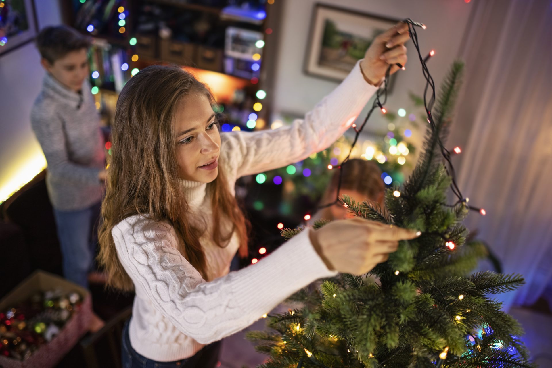 ragazza dispone luci sull'albero di natale
