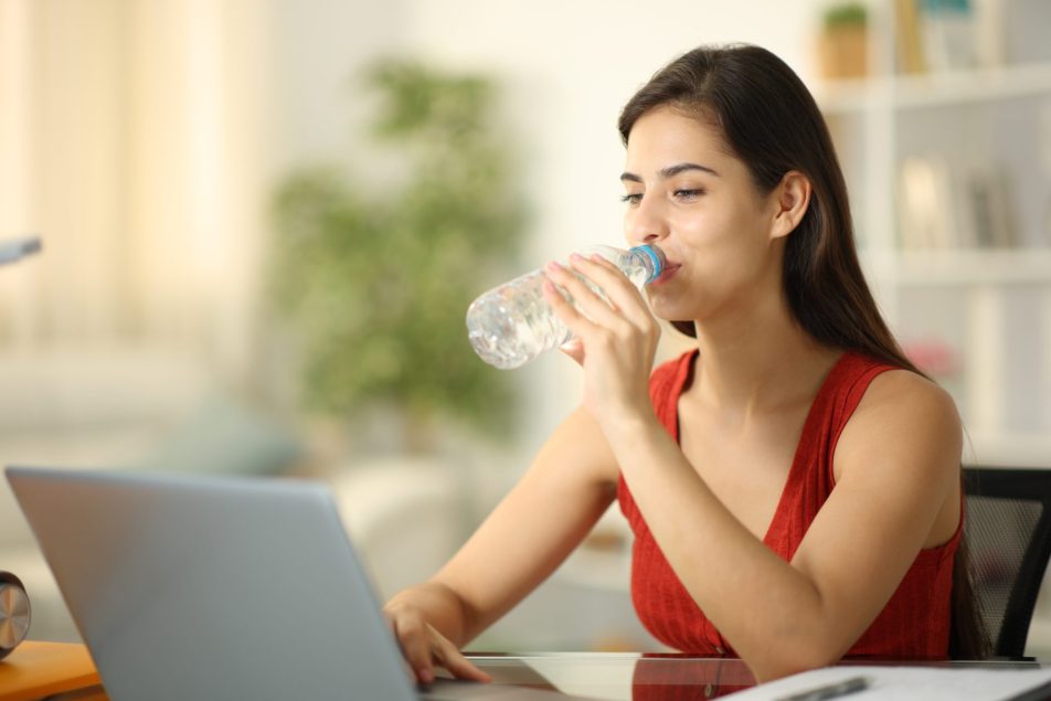microplastiche_cover giovane donna davanti al computer beve acqua da bottiglia