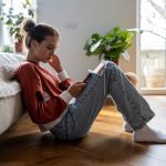 ragazza seduta sul pavimento guarda lo smartphone