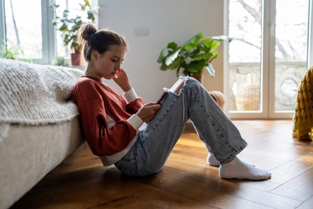 ragazza seduta sul pavimento guarda lo smartphone
