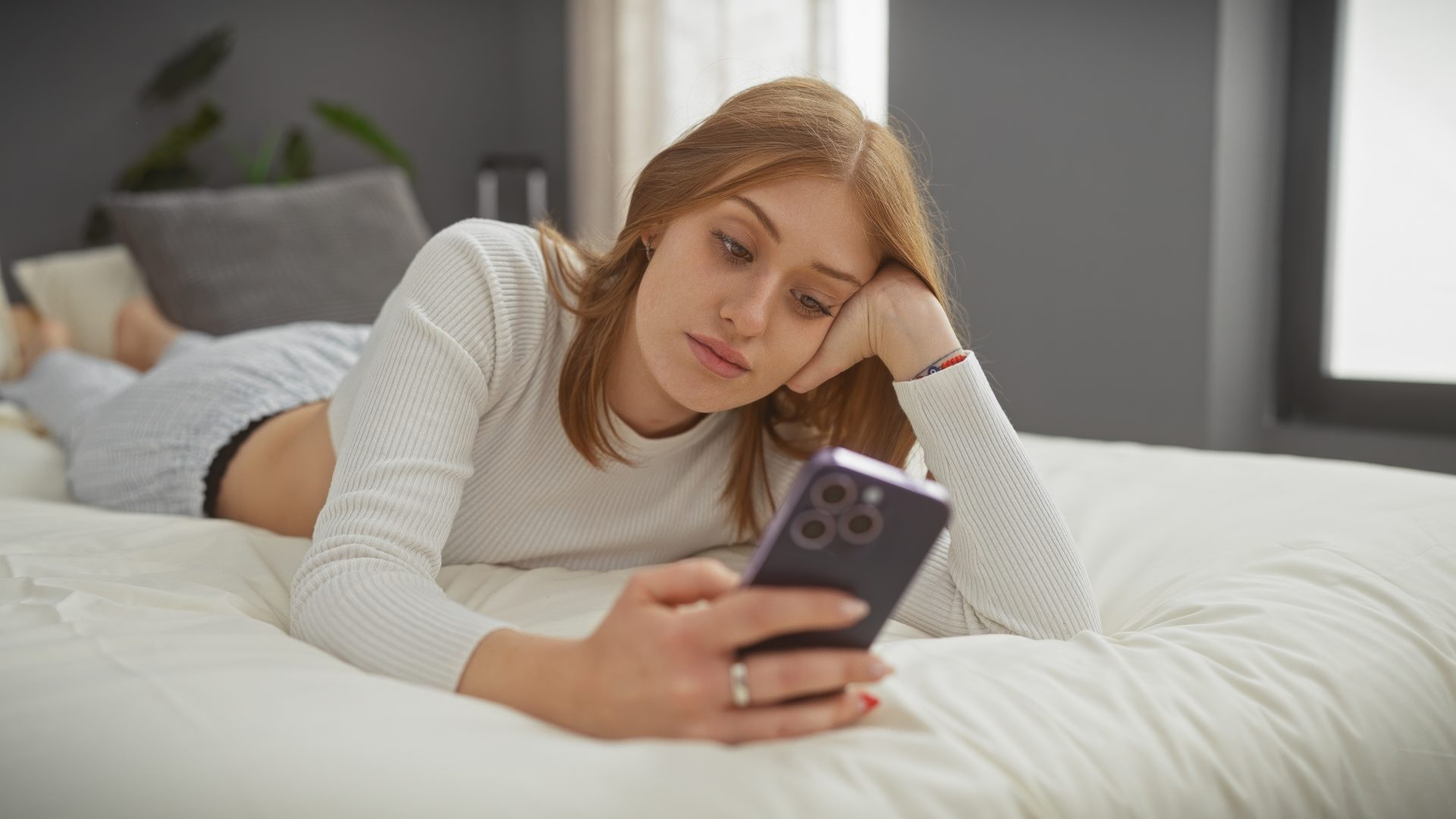 ragazza guarda telefono distesa sul letto