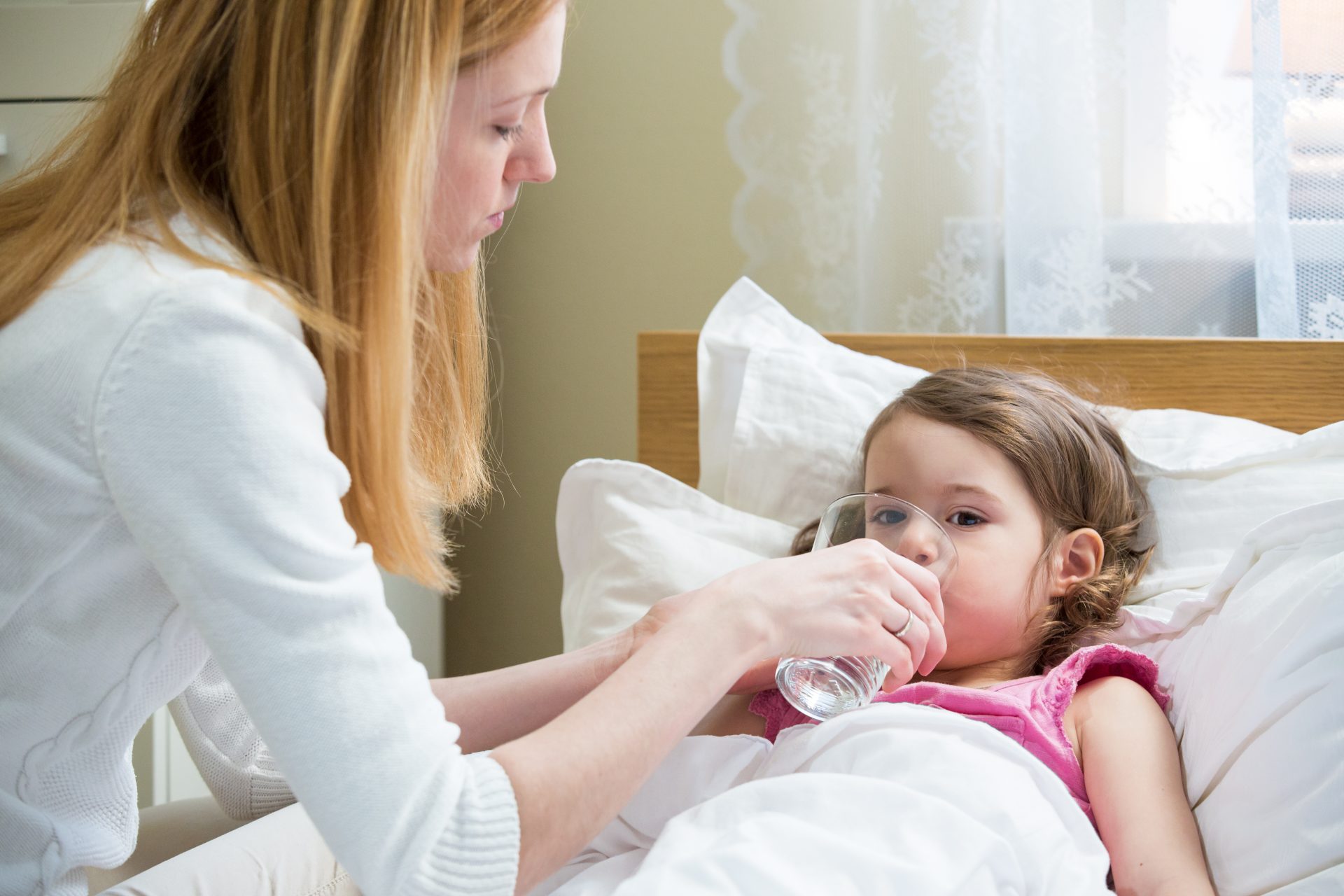 madre porge bicchiere acqua a bambina ammalata