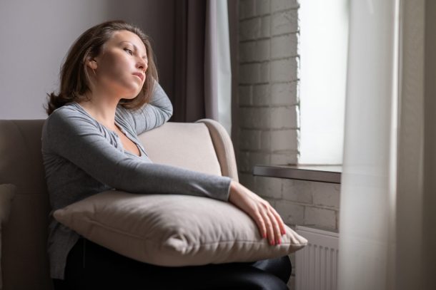 giovane donna pensierosa guarda fuori dalla finestra