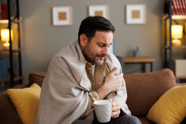 uomo ammalato con coperta e tazza in mano