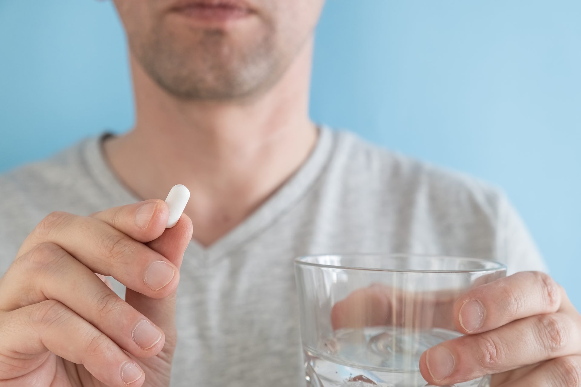 uomo prende pillola con bicchiere d'acqua