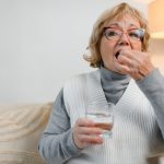 donna anziana prende pillola con bicchiere d'acqua