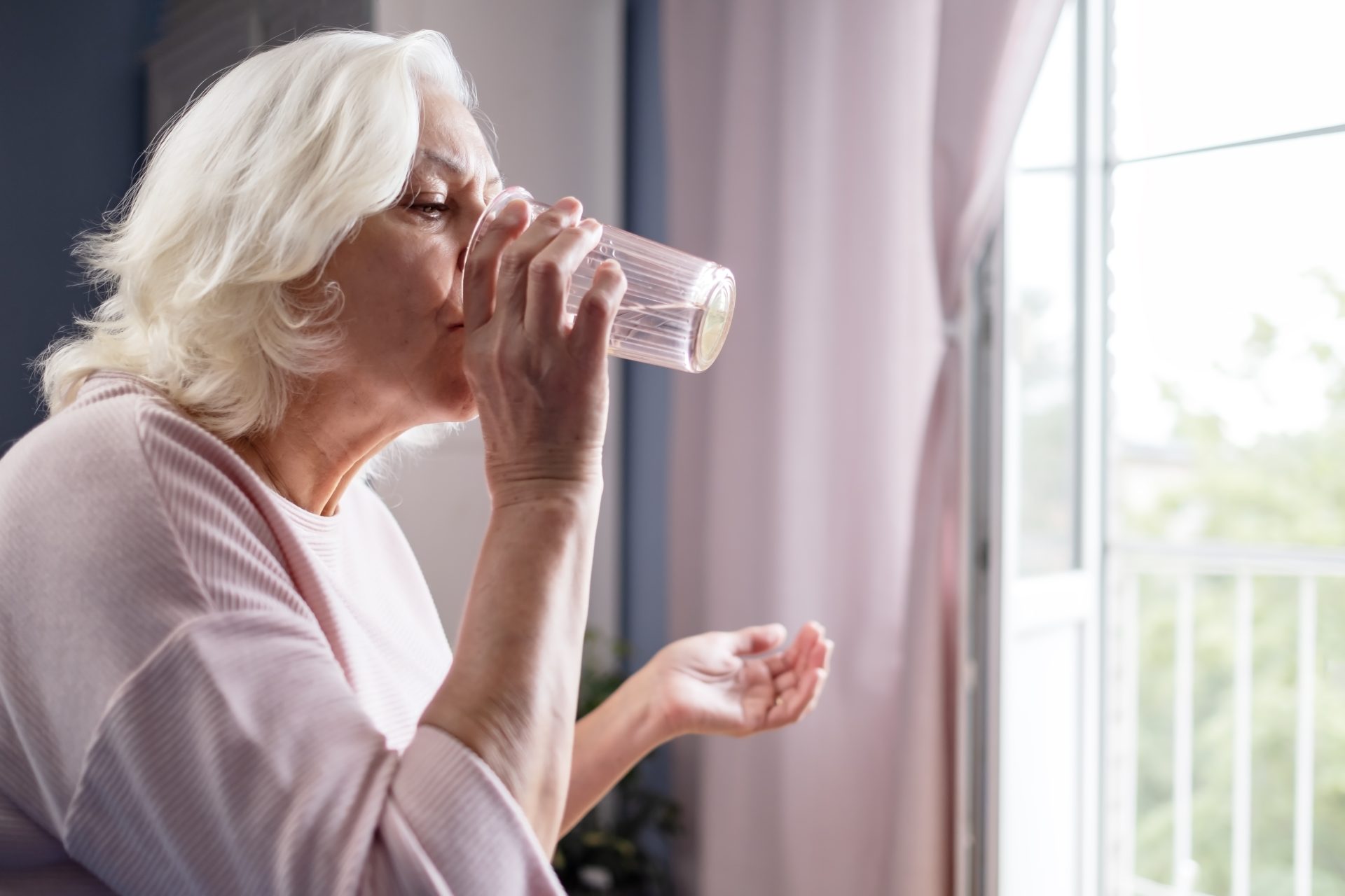 donna anziana beve bicchiere d'acqua