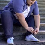 giovane uomo obeso si allaccia la scarpa