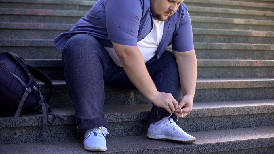 giovane uomo obeso si allaccia la scarpa