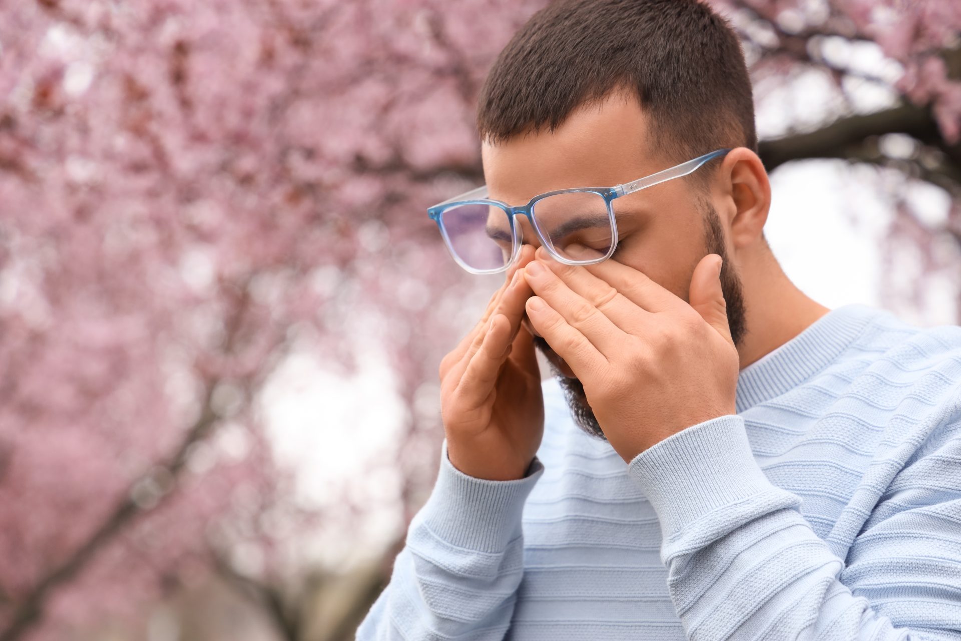 giovane uomo con prurito agli occhi per allergia ai pollini