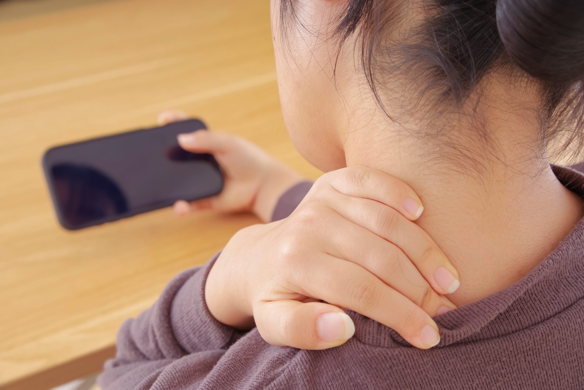 donna con dolore cervicale mentre usa smartphone