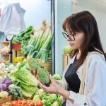 donna che osserva carciofi mentre fa spesa