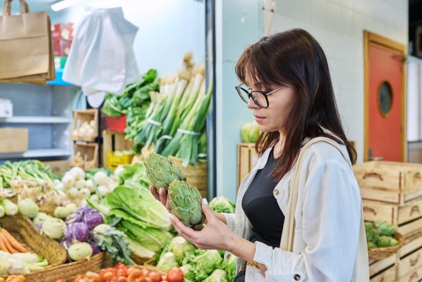 donna che osserva carciofi mentre fa spesa