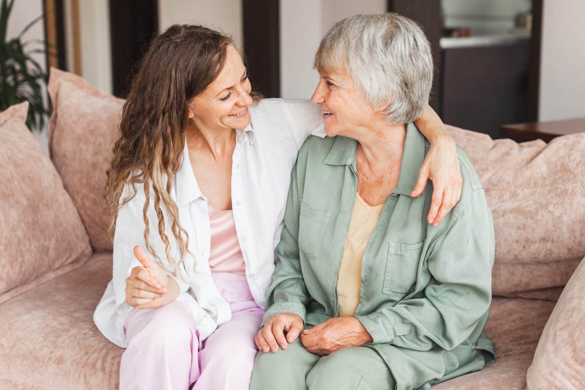 caregiver abbraccia donna anziana sul divano
