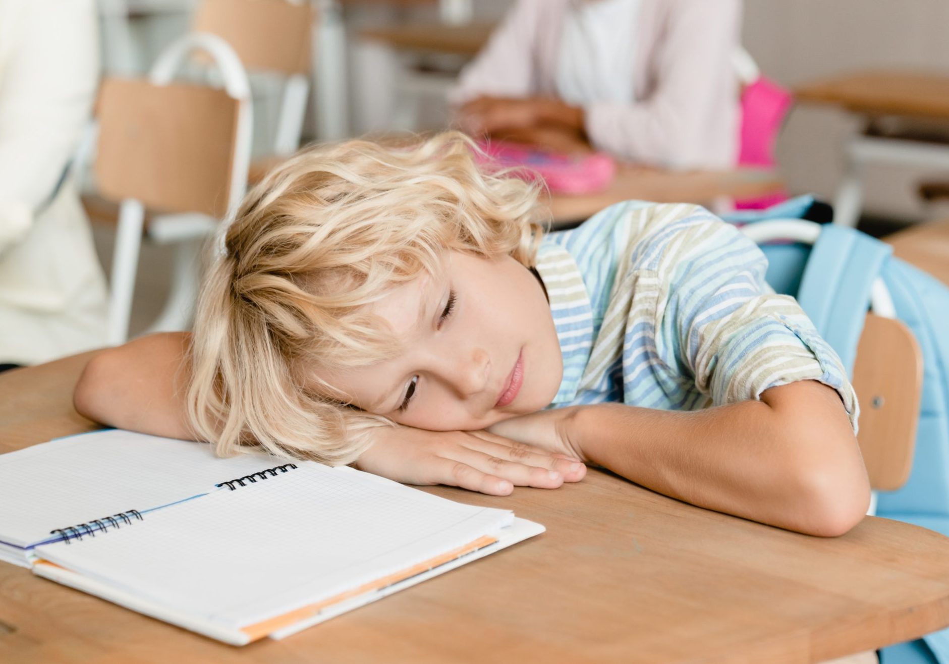 bambino stanco con testa poggiata sul banco di scuola