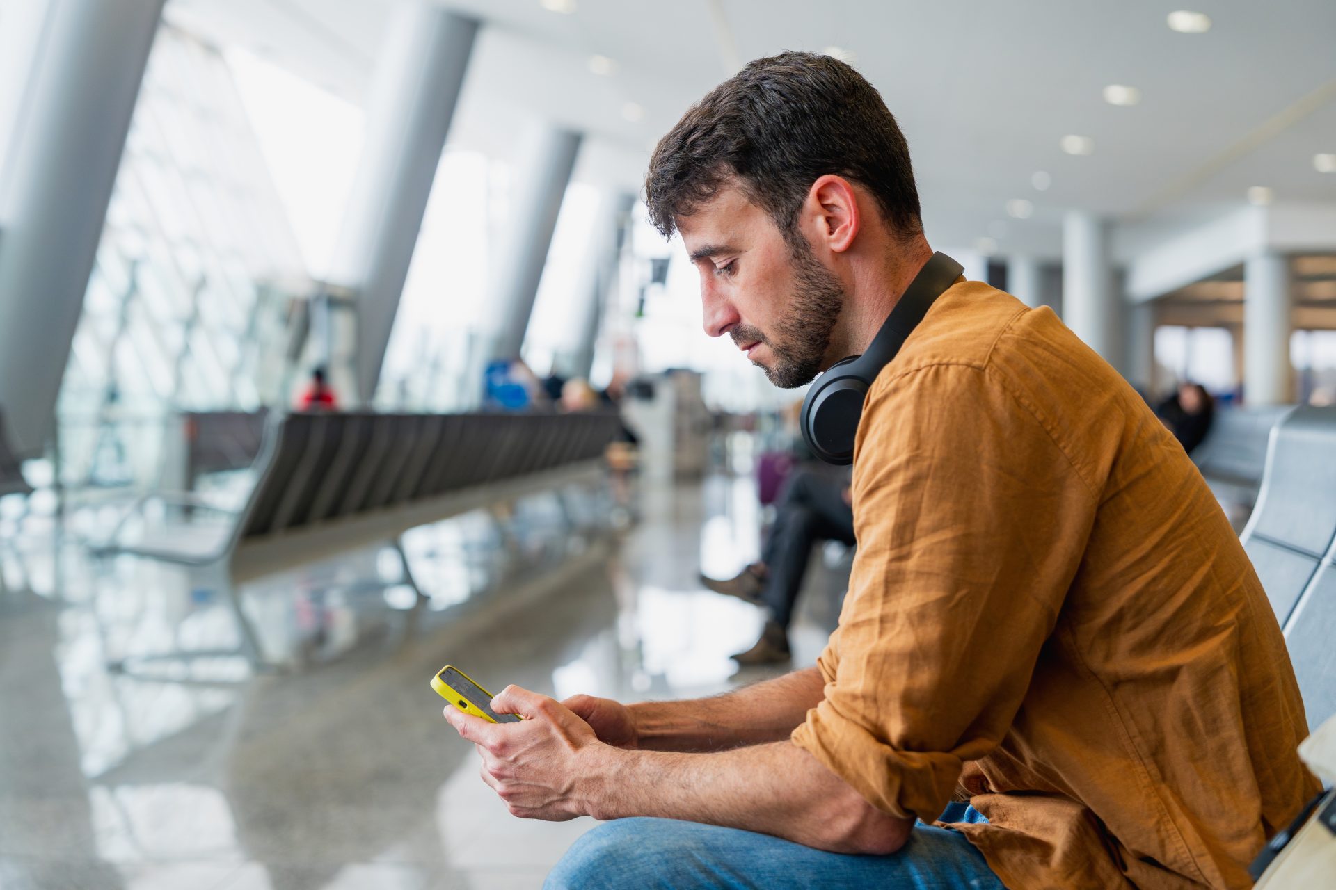 uomo utilizza smartphone seduto in aeroporto 