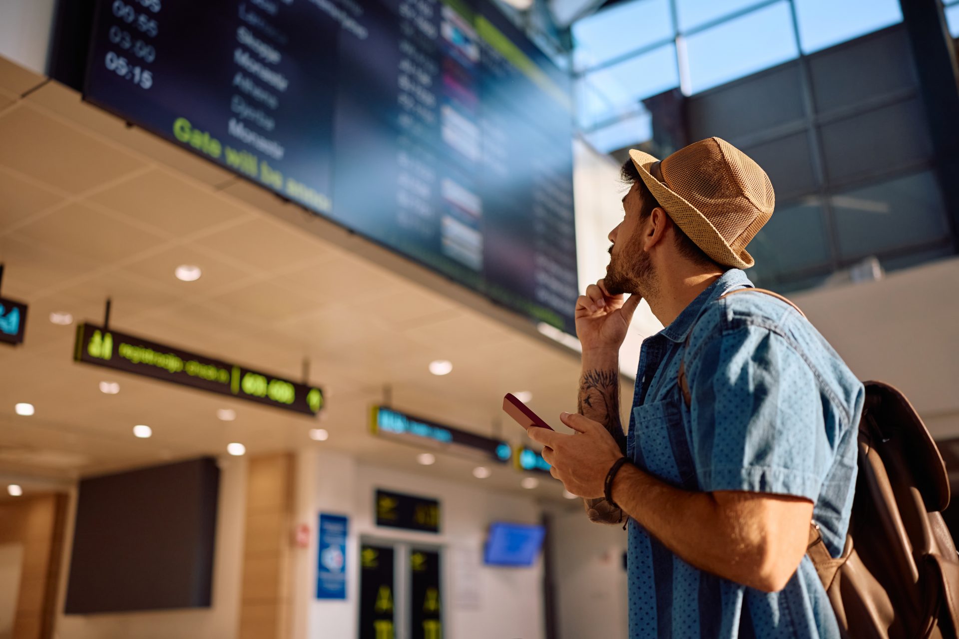 uomo guarda schermo delle partenze in aeroporto