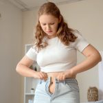 ragazza fatica a indossare paio di jeans