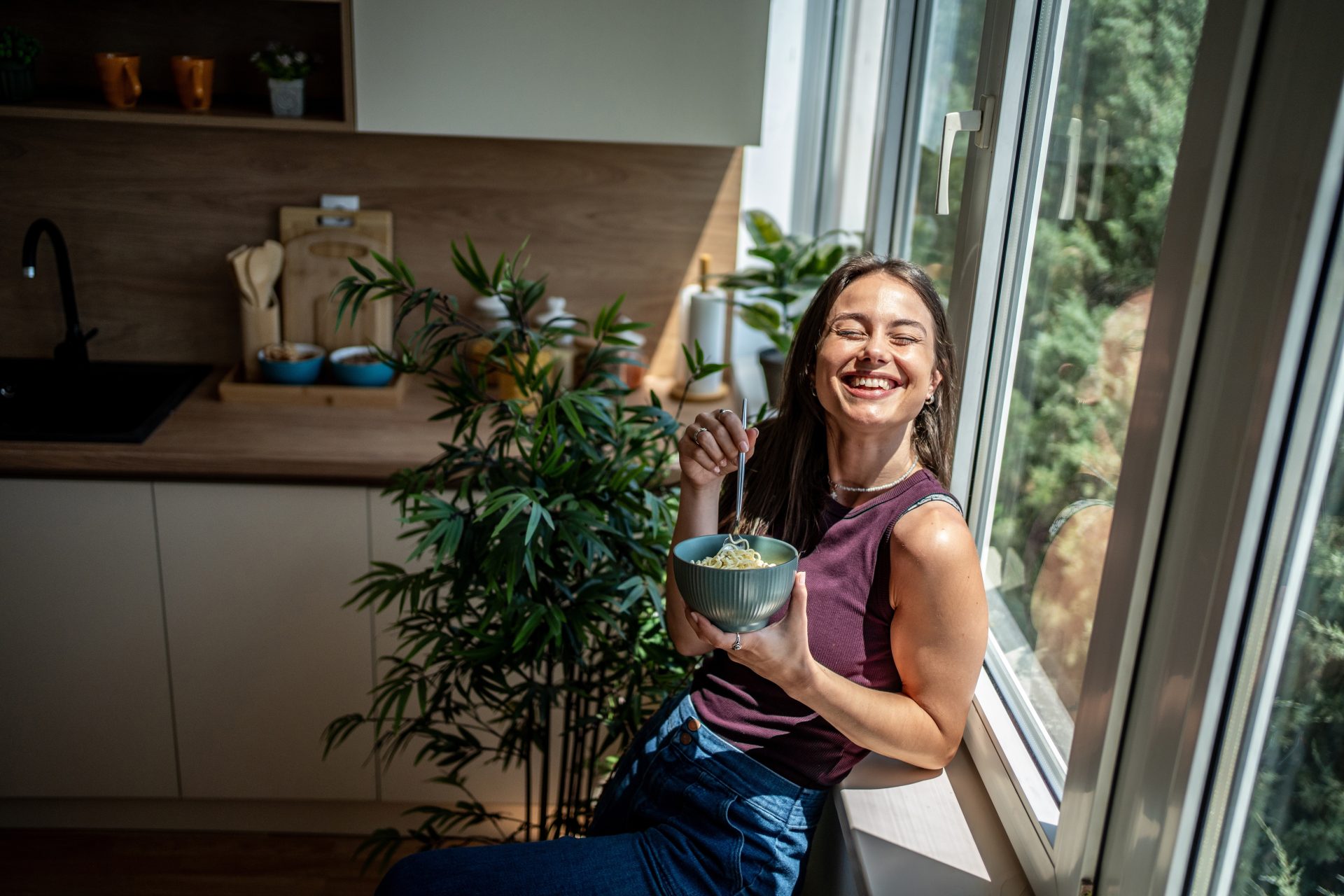 donna sorridente al sole davanti alla finestra 