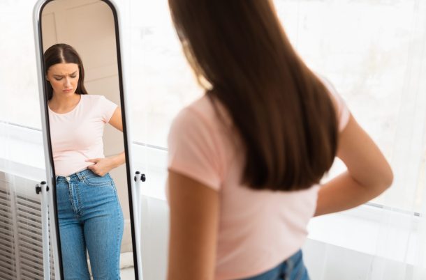 disturbi-comportamento-alimentare_cover giovane donna frustrata per il proprio aspetto fisico davanti allo specchio