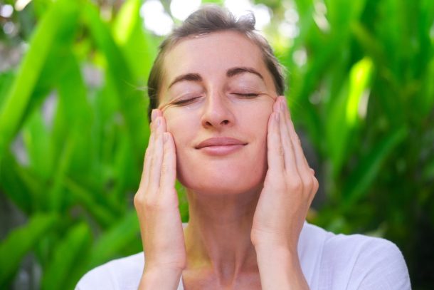 donna si tocca il viso all'aperto