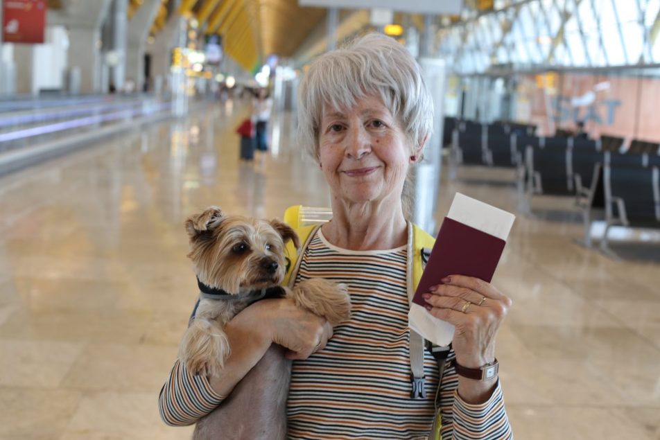 donna anziana con cagnolino in braccio e passaporto in mano