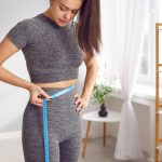 giovane donna in completo sportivo misura circonferenza addome