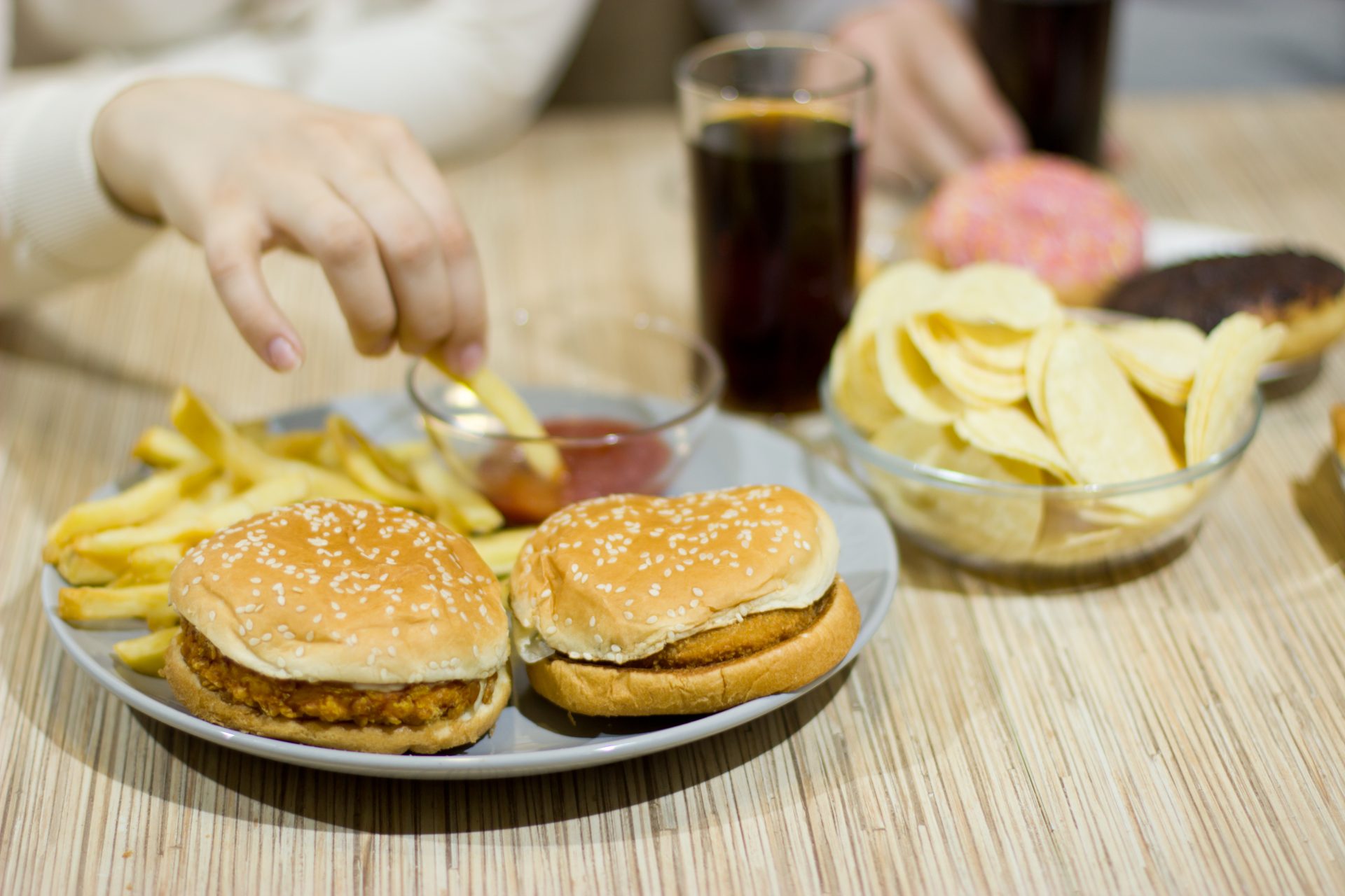 persona mangia patatine e hamburger