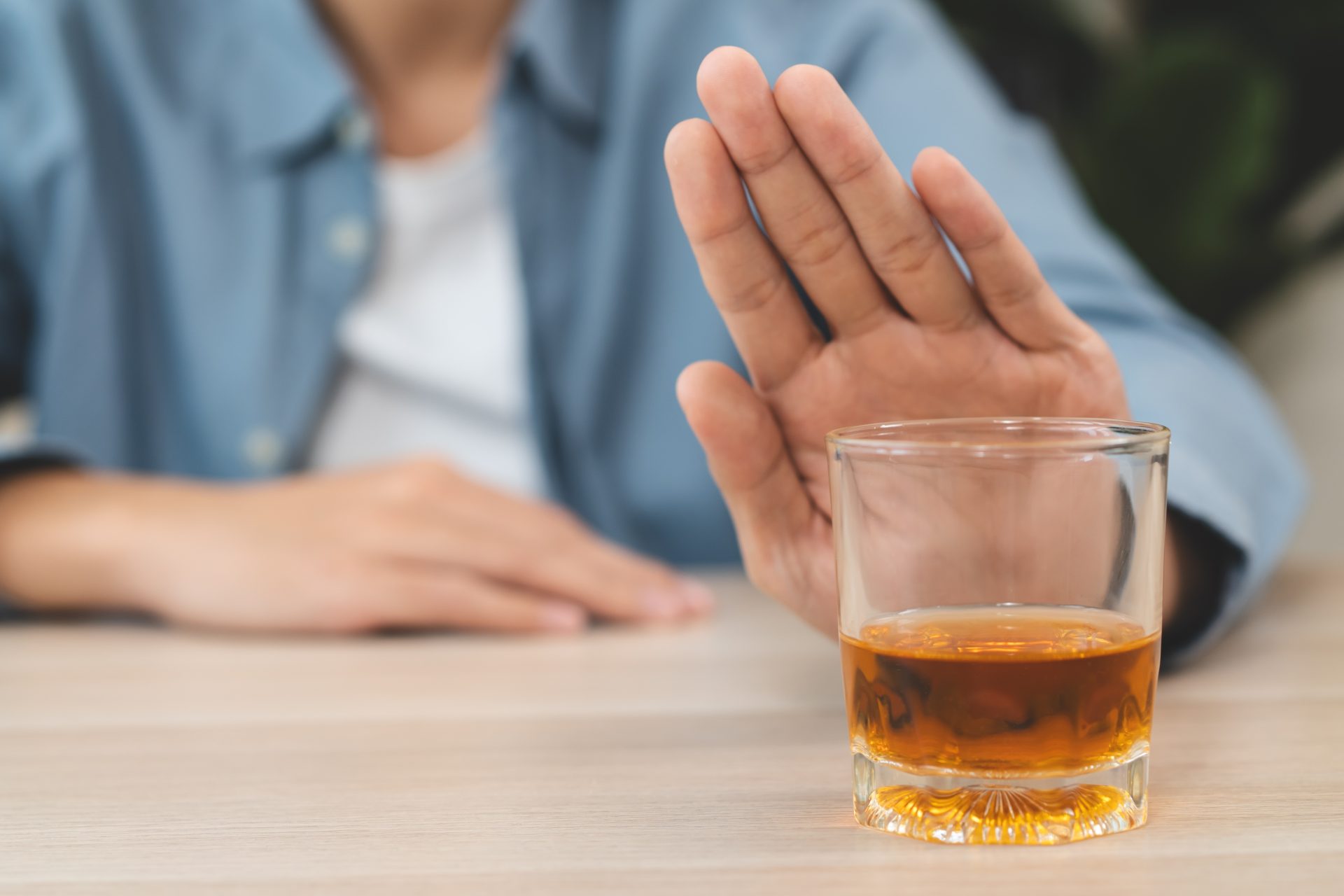 persona fa gesto di rifiutare bicchiere con alcol
