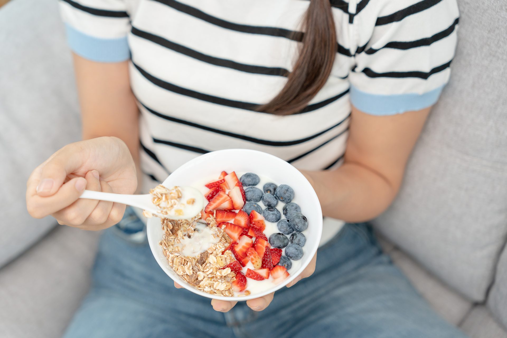 donna con ciotola di yogurt con avena, fragole e mirtilli
