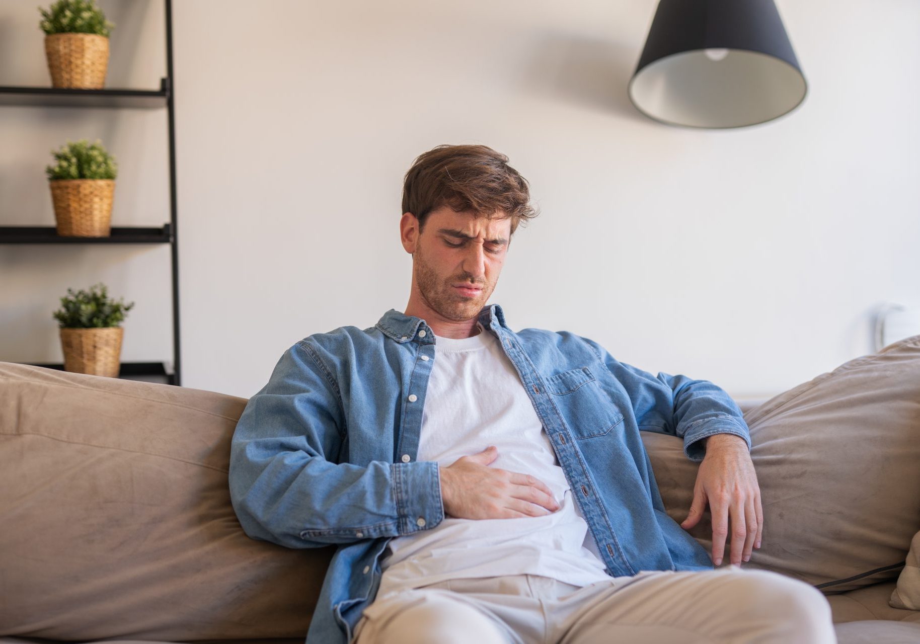 intestino-irritabile_cover giovane uomo seduto sul divano con mal di stomaco