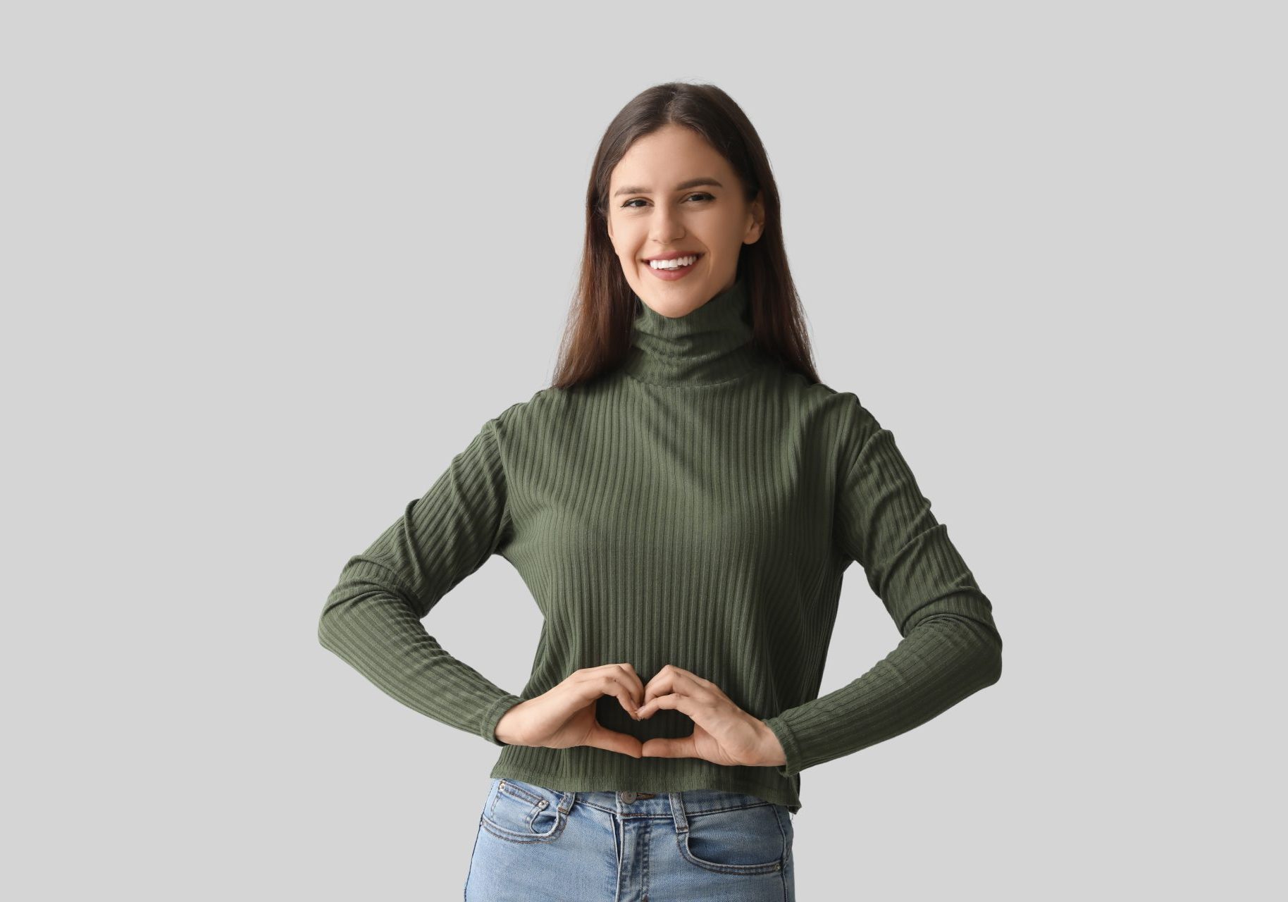 giovane donna sorridente con mani a cuore su addome