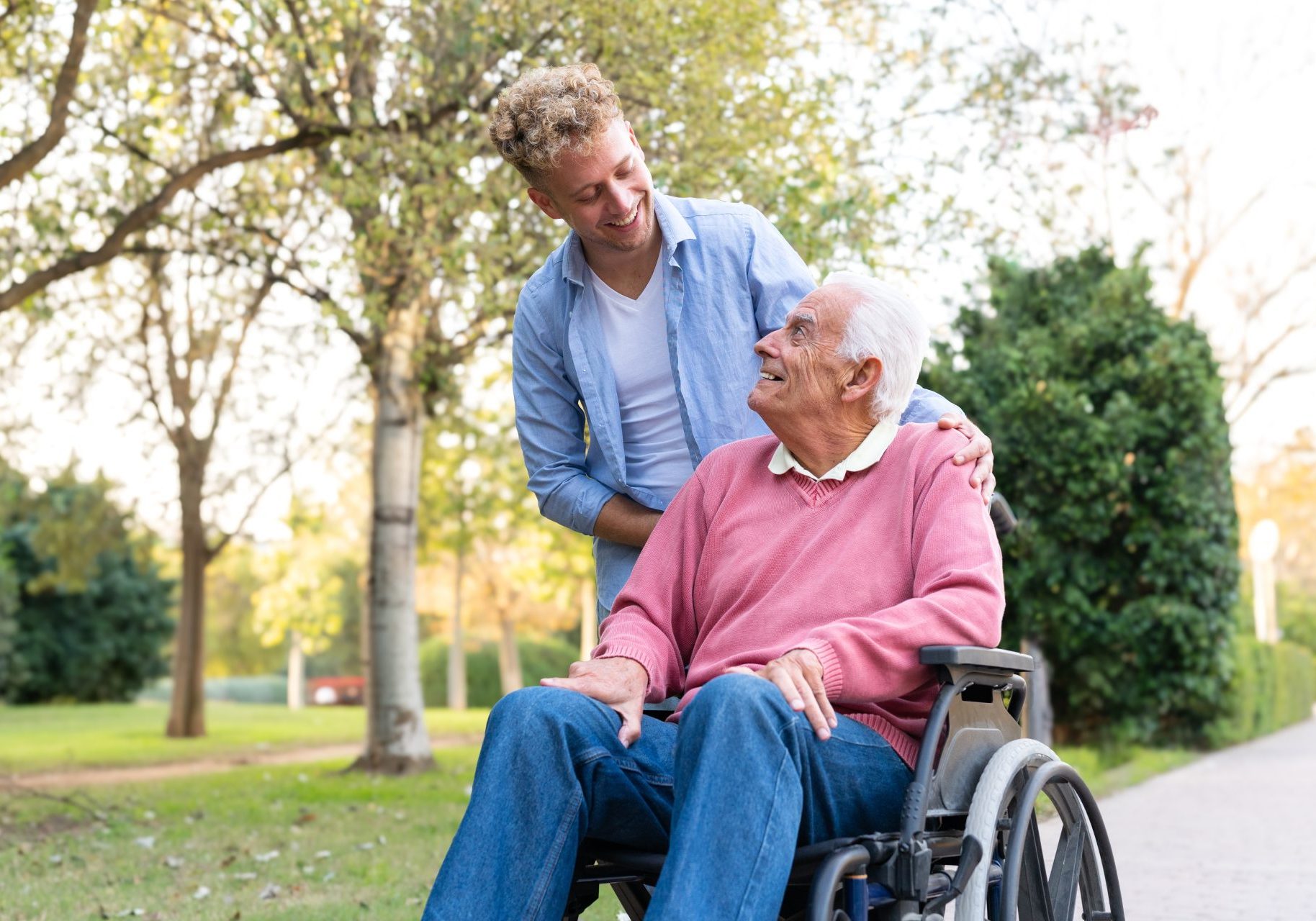 invalidita-permanente_cover caregiver sorride a uomo anziano in sedia a rotelle