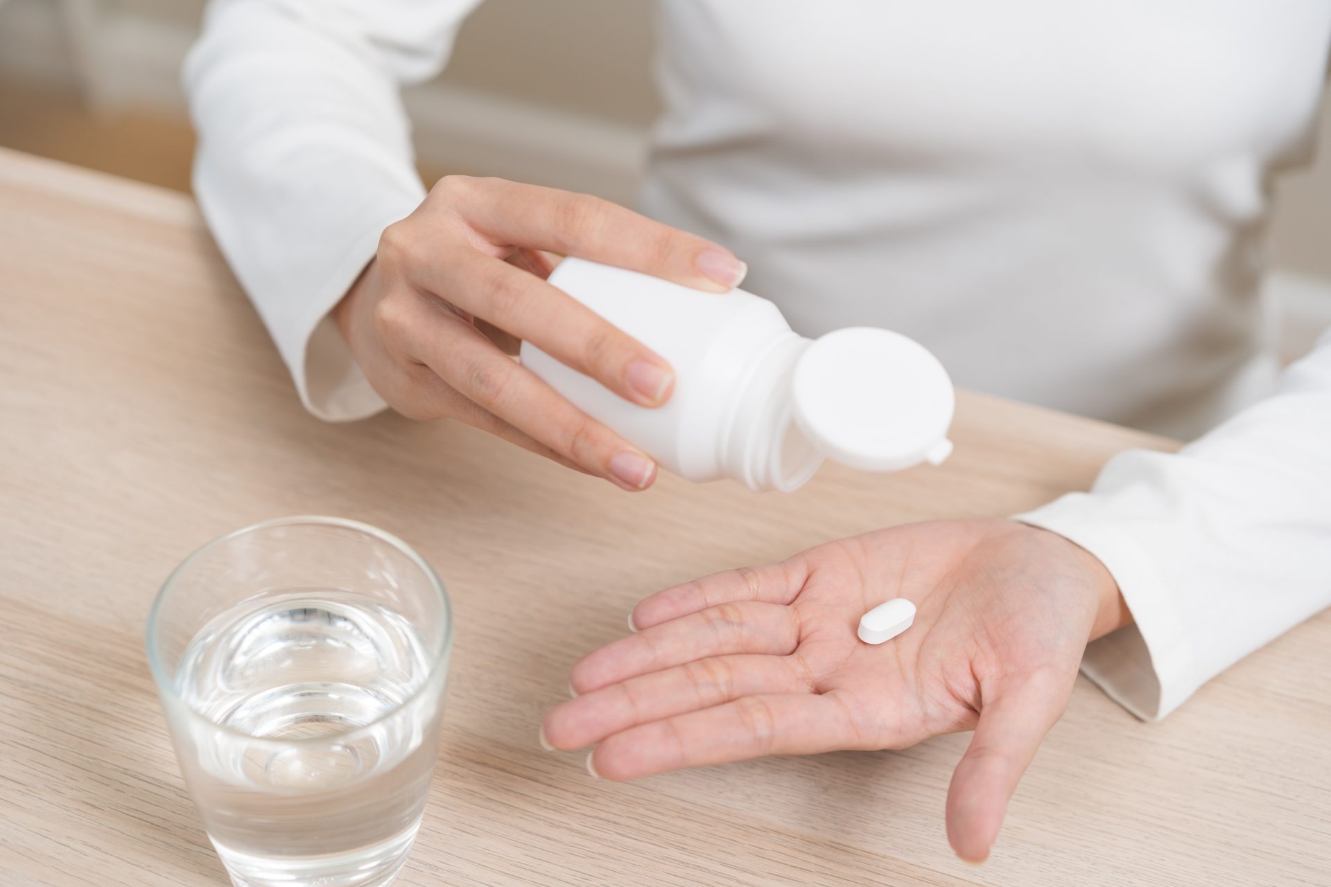 donna prende antibiotico con bicchiere d'acqua