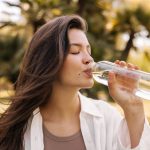 giovane donna beve acqua all'aperto