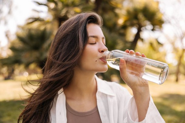 giovane donna beve acqua all'aperto